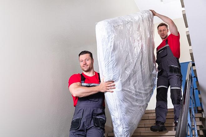 man carrying a heavy box spring out of a room in Alhambra, CA